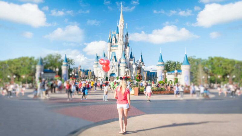 woman holding a red ballon in front of the disney castle on an Orlando spring Break Vacation