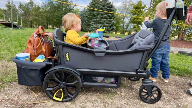 child sitting in the veer wagon stroller with brother next to it