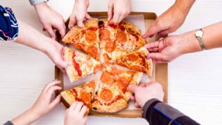 peoples hands grabbing slices of pizza