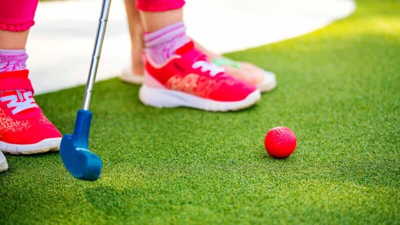 kid playing miniature golf