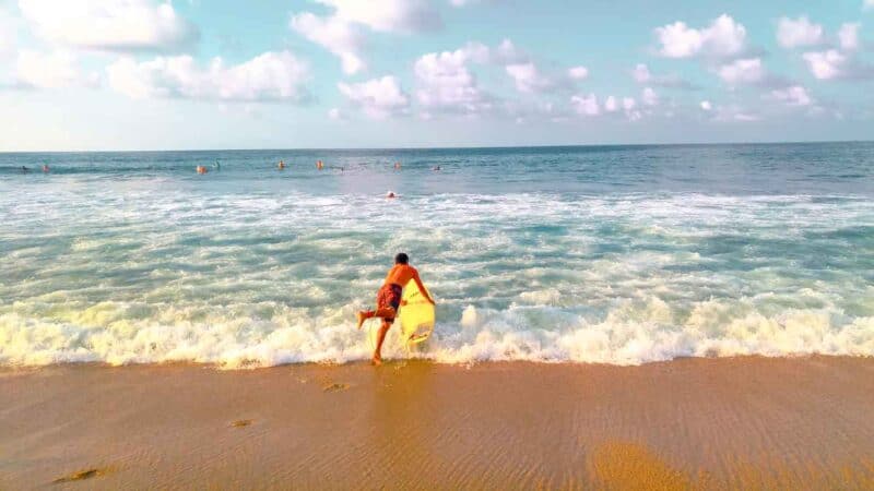 surfer heading out in the ocean to go surfing