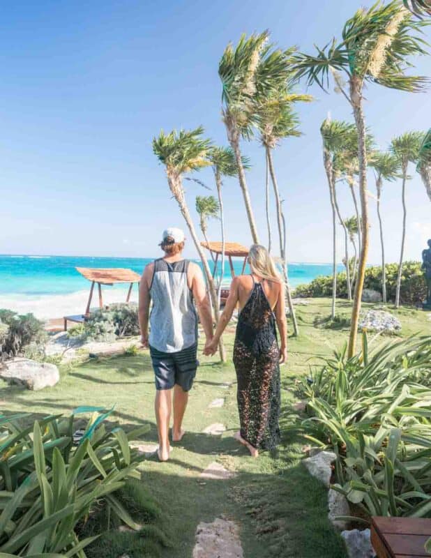 couple holding hands in Tulum Mexico looking at the beach