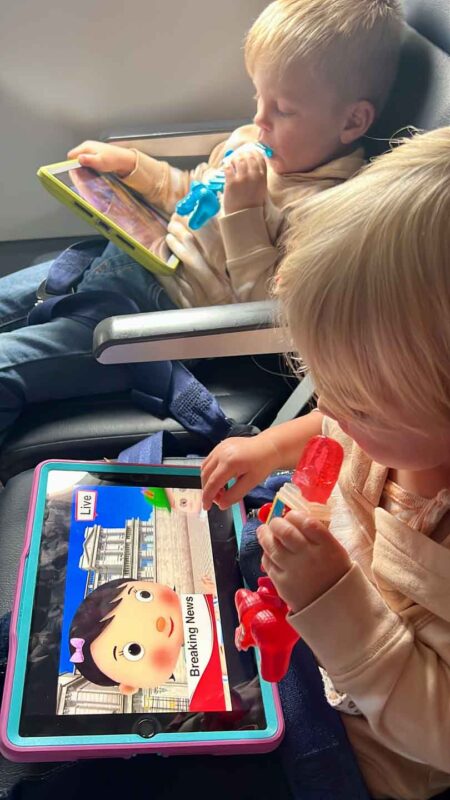 two toddlers flying on airplane with sucker