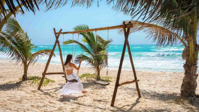 woman on a swing on the beach in Tulum Mexico