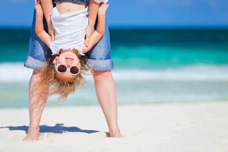 dad holding daugher upside down on the beach