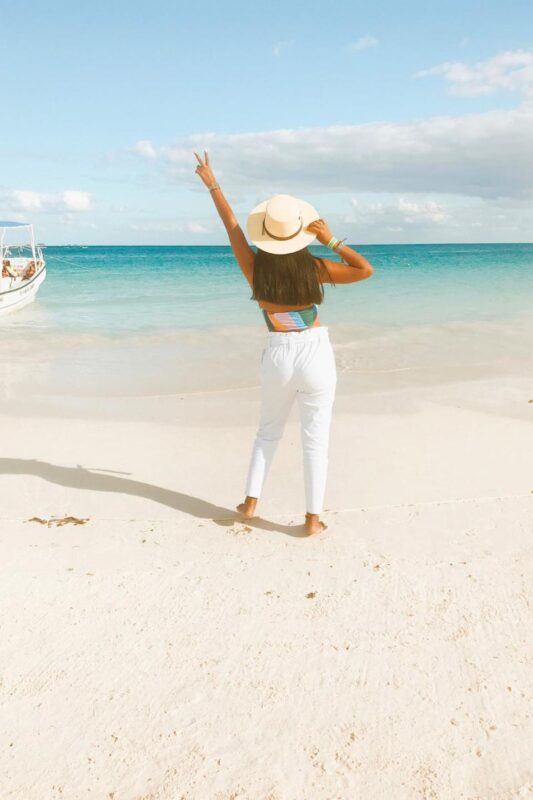 woman on the beach in Tulum Mexico making a pease sign