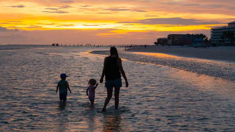 Family walking on Fort Myers beach at sunset