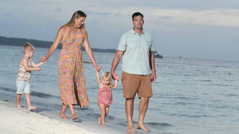 family with young kids walking on the beach 