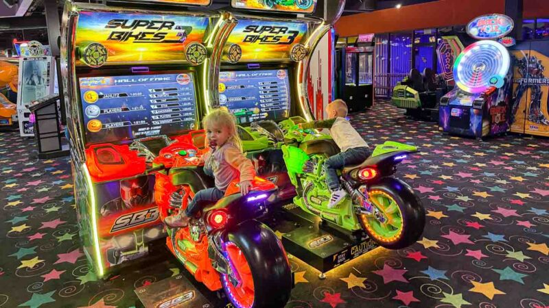Children playing a motorcycle riding game at Johns Incredible Pizza