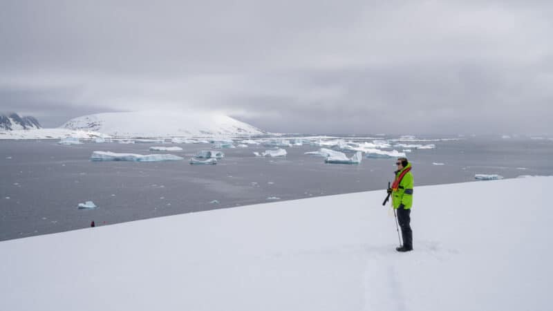 women standing in Antarctica wearing a coat for Antarctica and rain pants