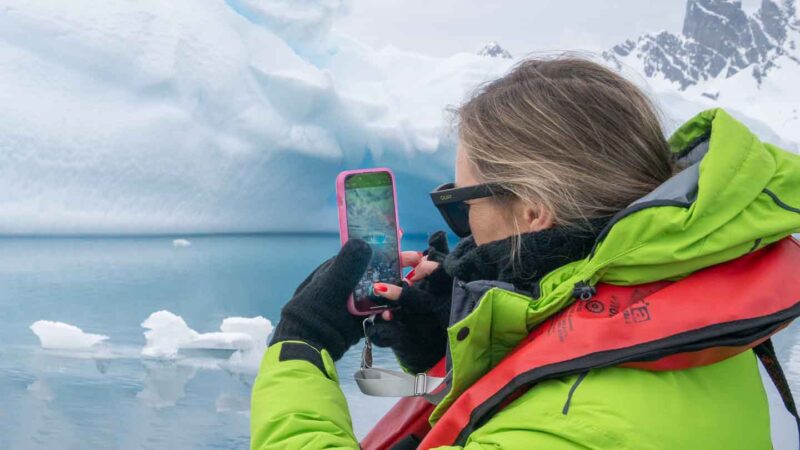 woman taking a picture in Antarctica wearing flip gloves a must pack for Antarctica