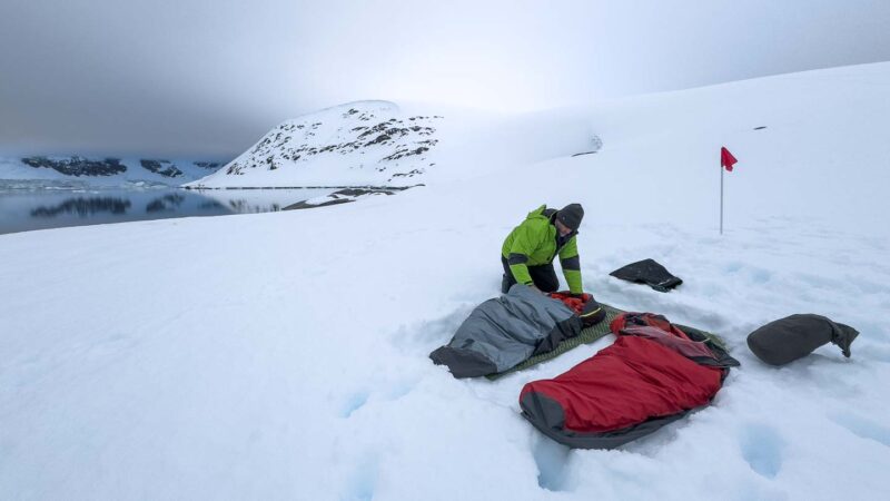 camping in Antarctica what to wear - man setting up sleeping bags.