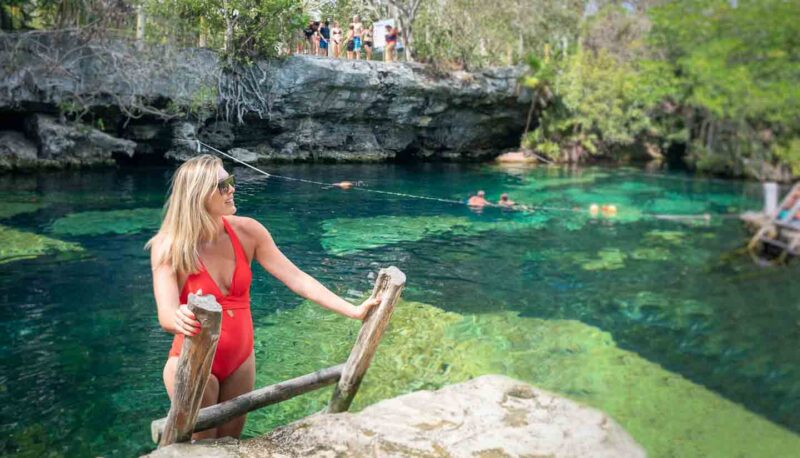 Woman in a red bathing suit on a ladder exiting Cenote Cristalino - top cenotes in Tulum