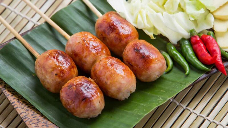 Sai Krok Isan or Isaan Sausage on a stick with peppers Bangkok street food