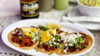 Al Pastor Tacos with pineapple, onions, and cilantro on top with a Modelo beer at a restaurant